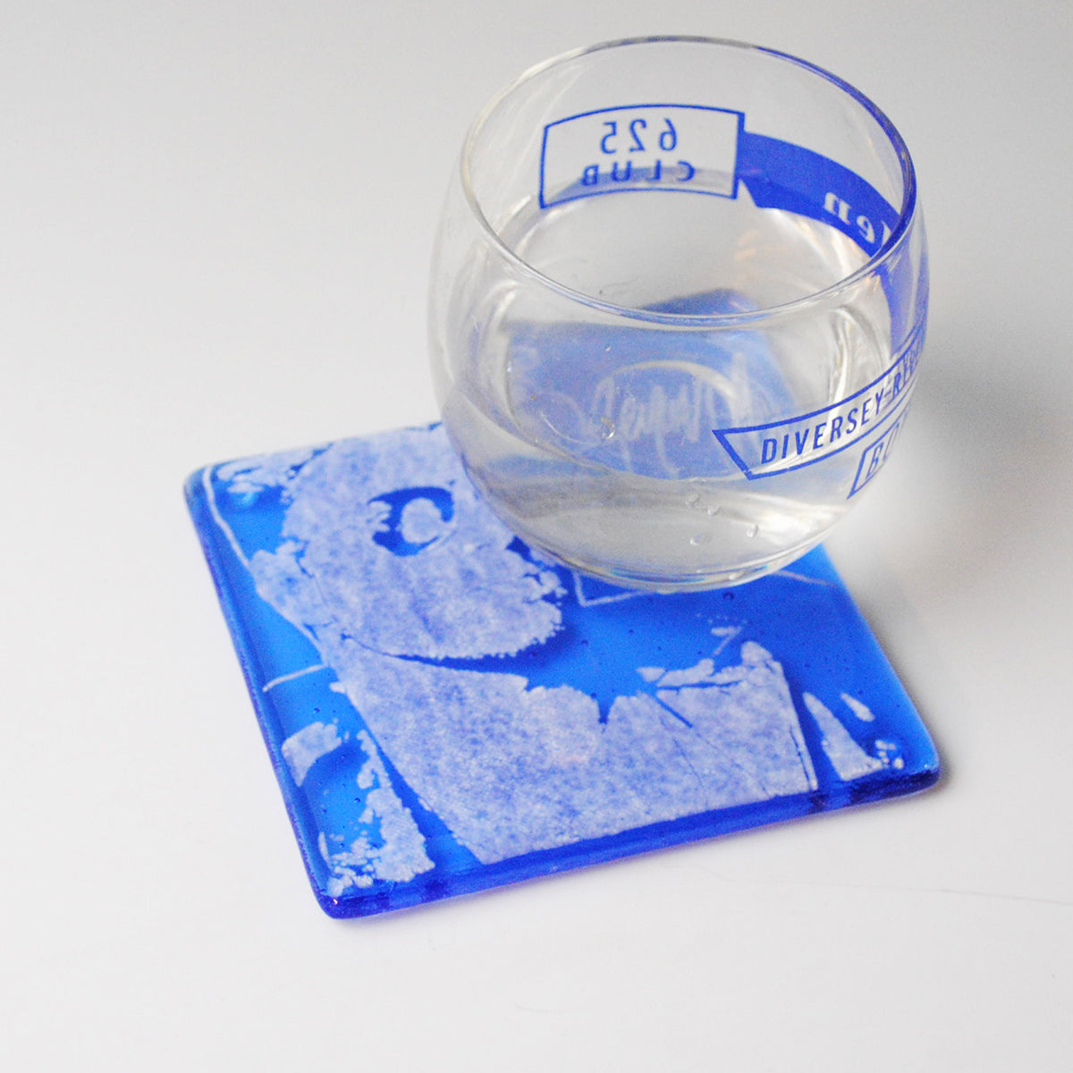 a glass of water sitting on top of a coaster