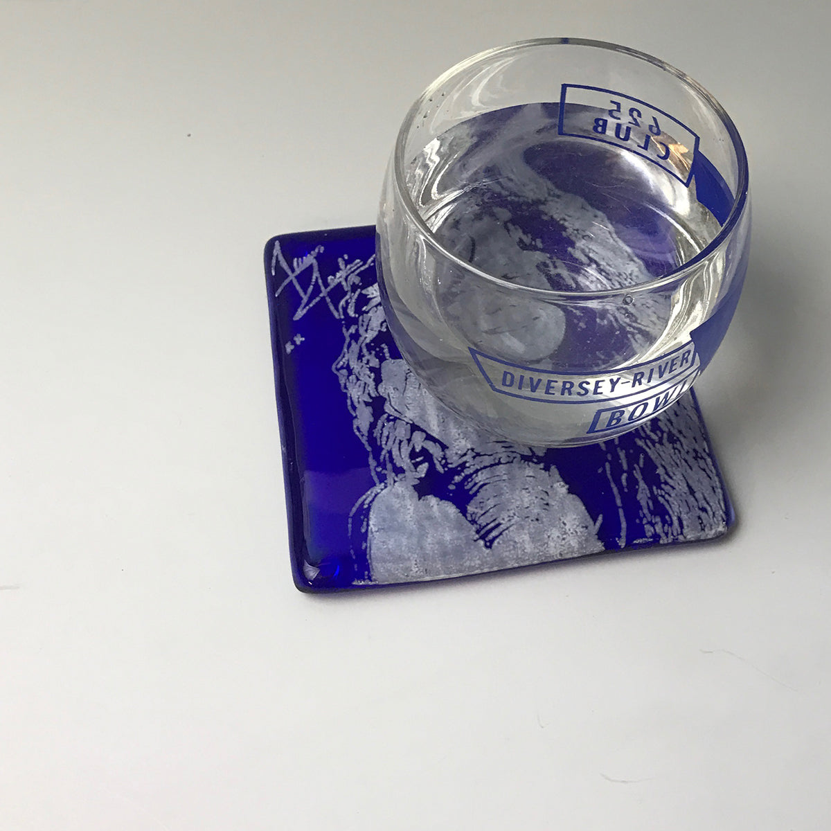 a glass of water sitting on top of a coaster