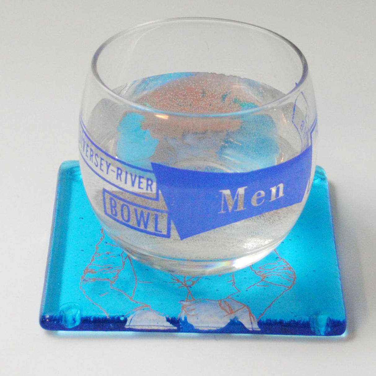 a glass of water sitting on top of a blue coaster