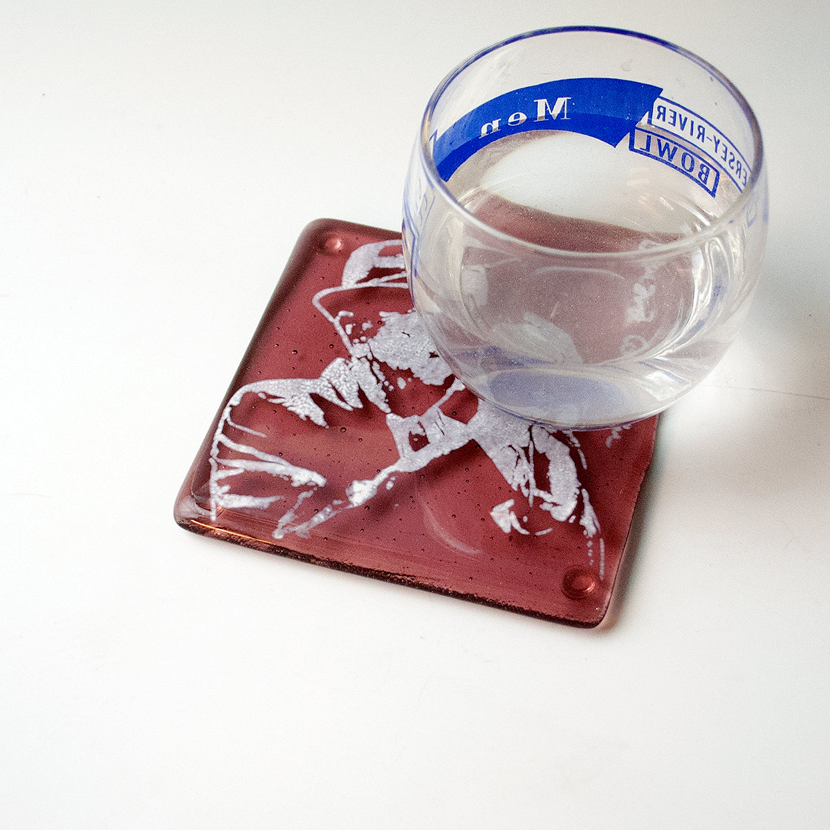 a glass of water sitting on top of a red coaster