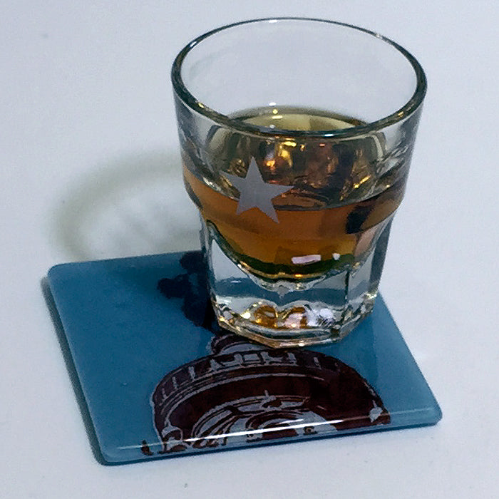 a glass of alcohol sitting on a coaster