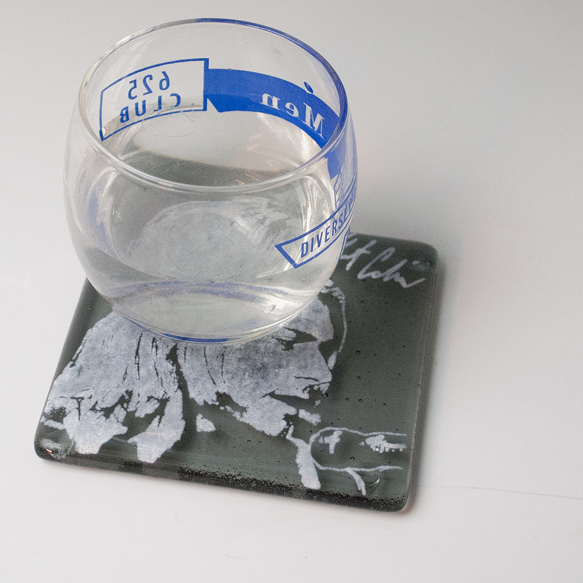 a glass of water sitting on top of a coaster