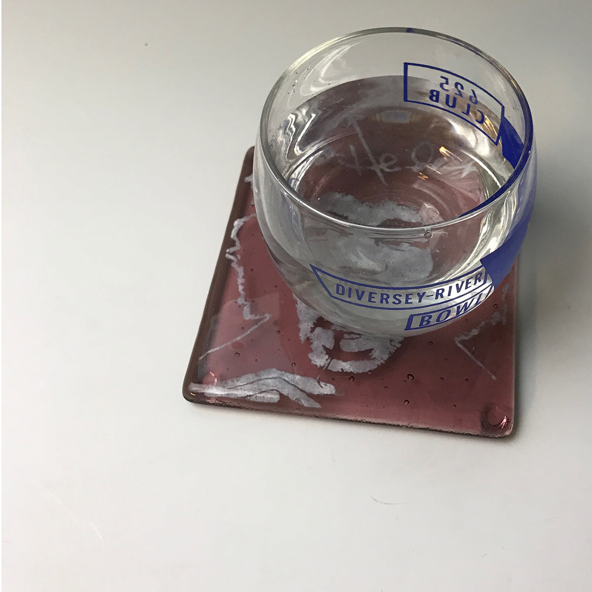 a glass of water sitting on top of a red coaster