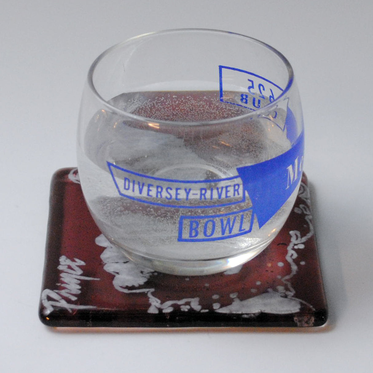 a glass of water sitting on top of a coaster