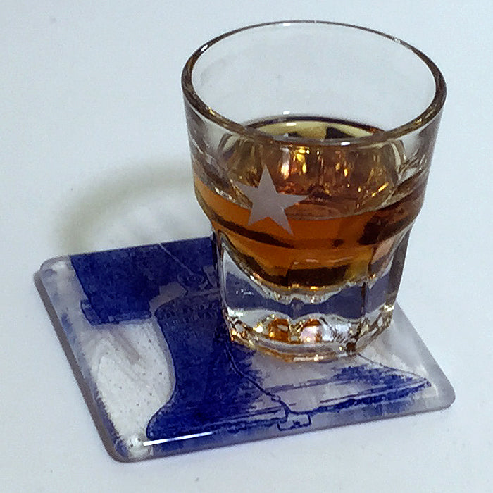 a glass of whiskey sitting on top of a coaster