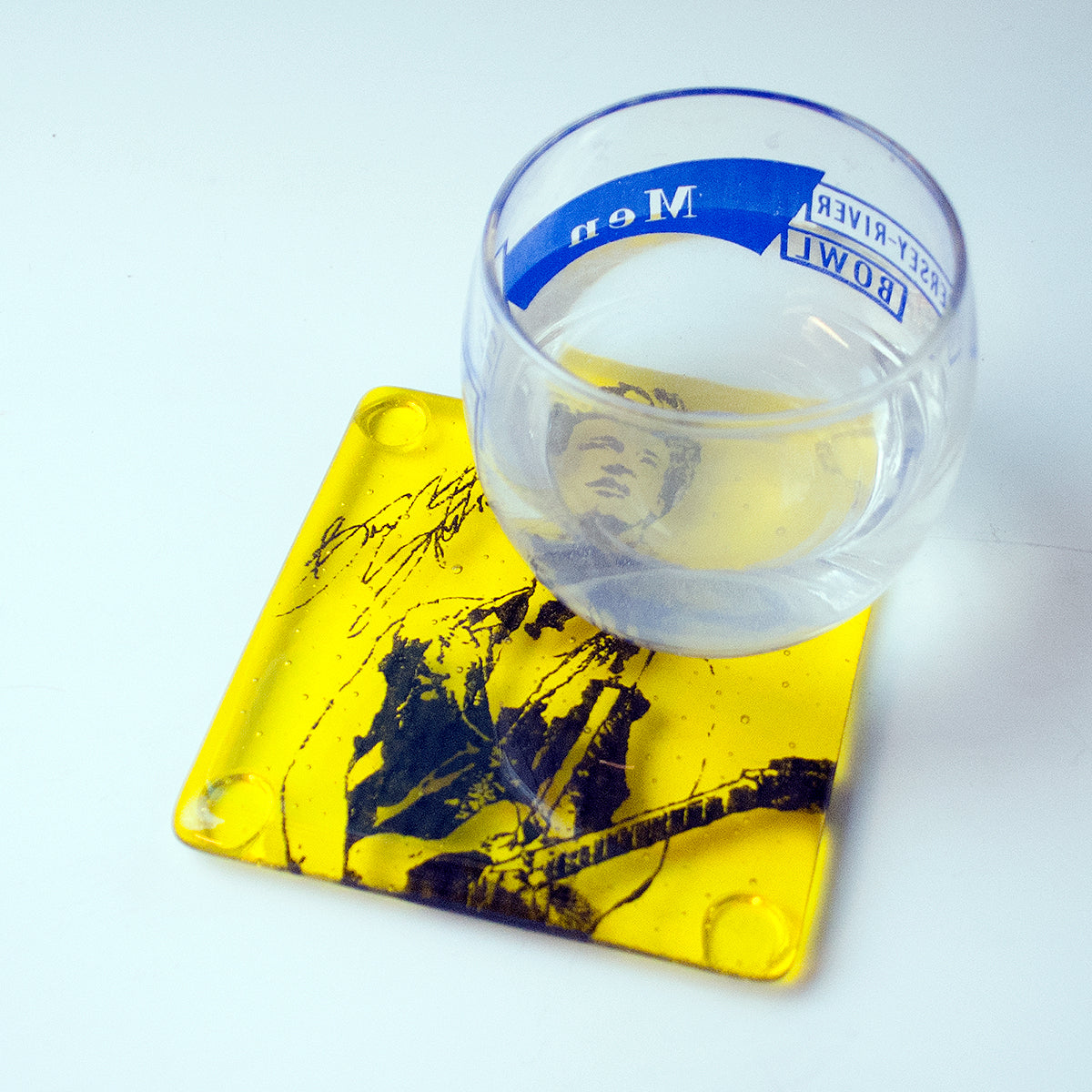 a glass of water sitting on top of a yellow coaster