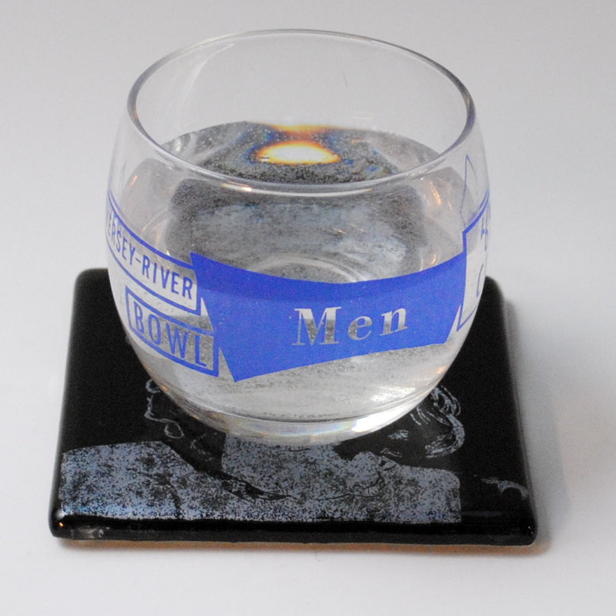 a glass of water sitting on top of a coaster