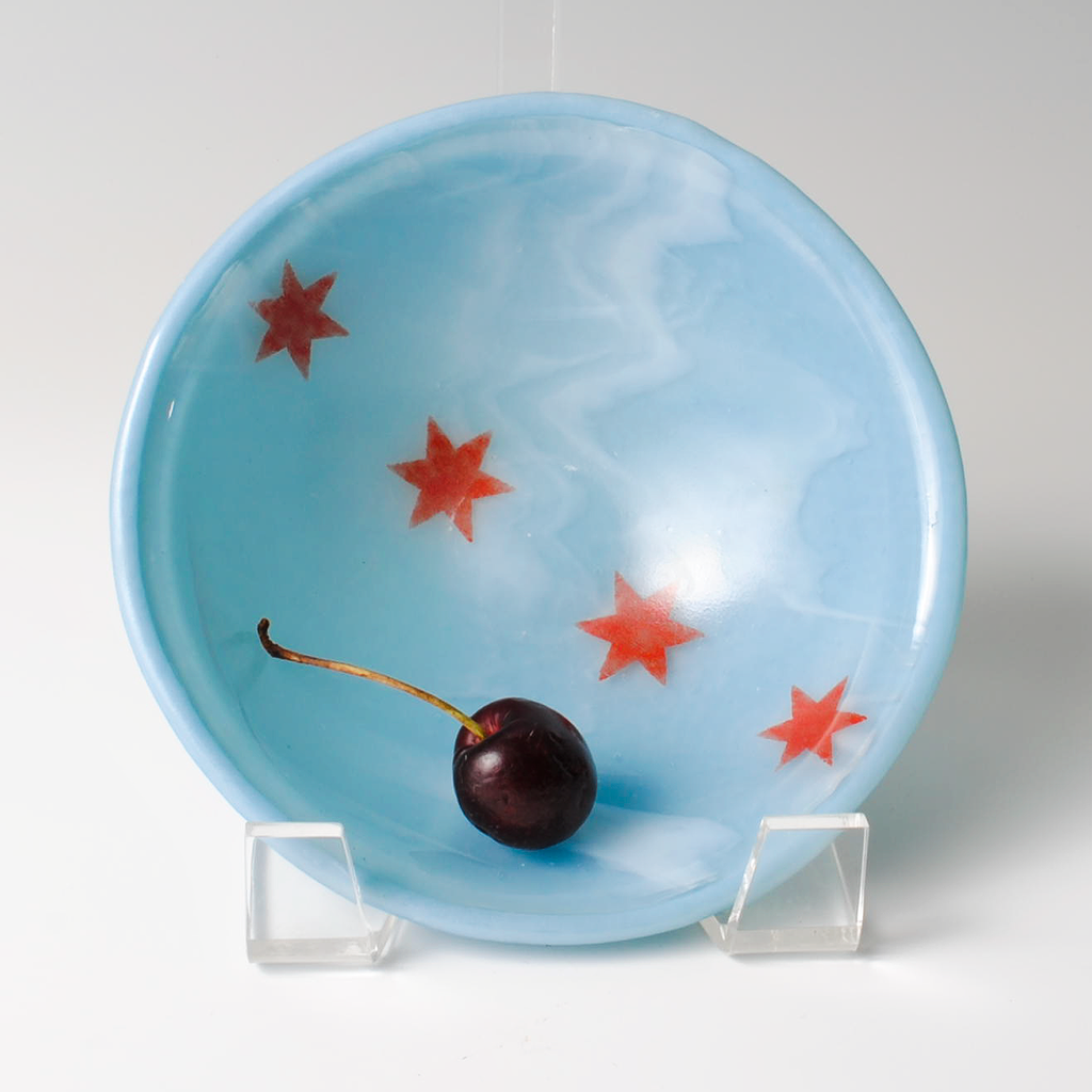 a blue bowl with red stars and a cherry