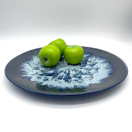 Decorative plate with a floral design holding three green apples on a white background