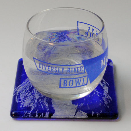 a glass of water sitting on top of a blue coaster