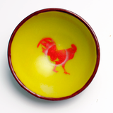 a yellow bowl with a red rooster painted on it
