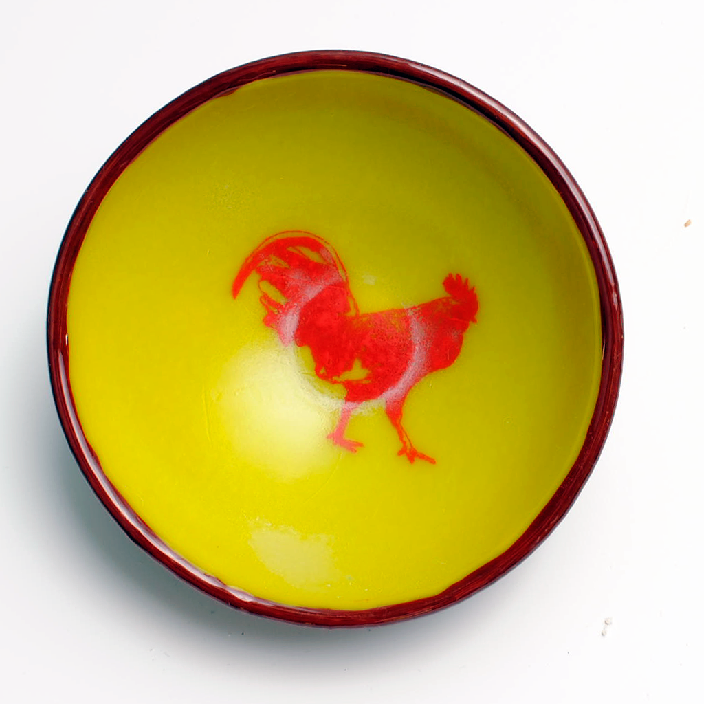 a yellow bowl with a red rooster painted on it